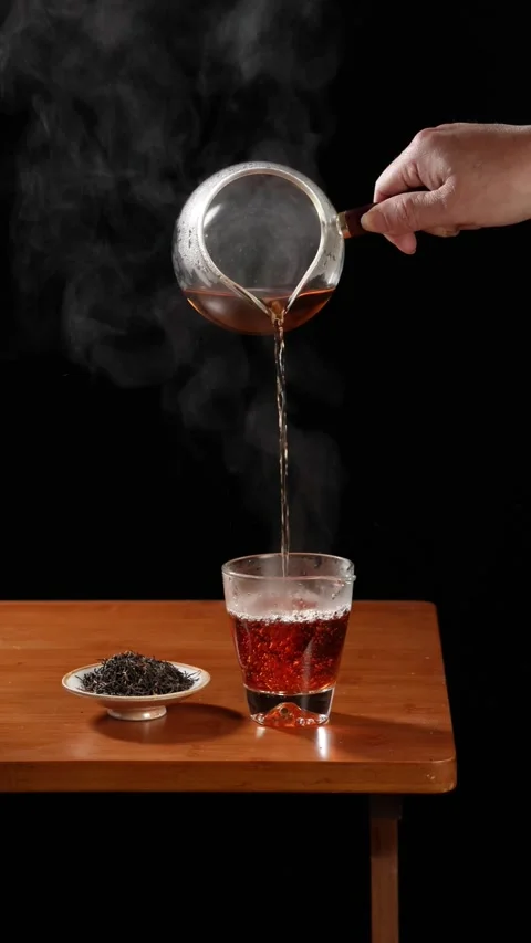 Slow Motion Pouring Hot Black Tea Into Glass Cup on Wooden Table Stock Footage 340006203