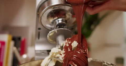 Slow motion pouring melted chocolate into a stand mixer with cake ingredients Stock Footage 247786142