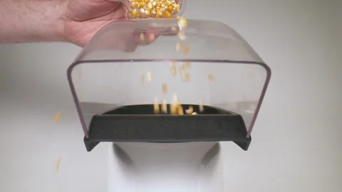 Slow motion pouring popcorn kernels into an air popper. Stock Footage 130835487