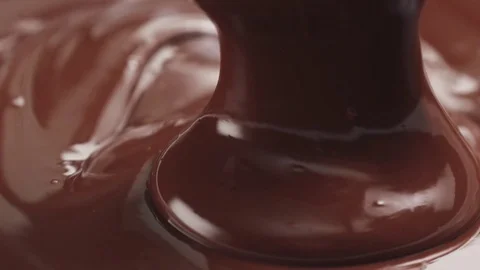 Slow motion pouring premium dark melted chocolate from big spoon Stock Footage