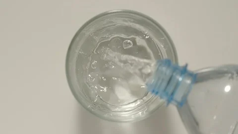 SLOW MOTION: Pouring pure water from a plastic bottle into a glass - Top View Stock Footage