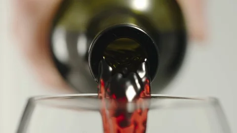SLOW MOTION: Pouring red wine from a bottle into a glass - Macro Stock Footage 101816992