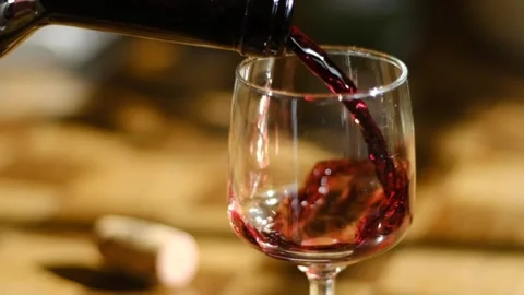 Slow Motion Pouring Red Wine into Glass in Warm Ambient Light Stock Footage 250639742