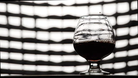 Slow motion of pouring red wine or brandy into glass with camera motion Video stock 254548805