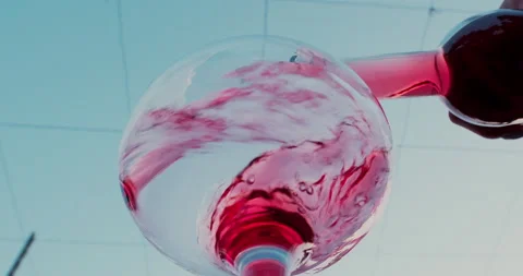 Slow motion of pouring rose wine from bottle into glass against blue sky Stock Footage 233283903