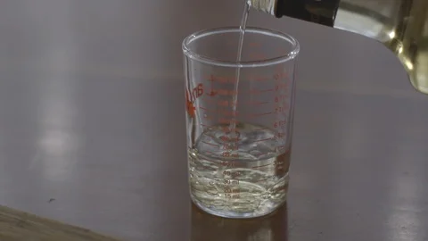 Slow motion pouring vinegar into a glass, stirring Stock Footage 88409558