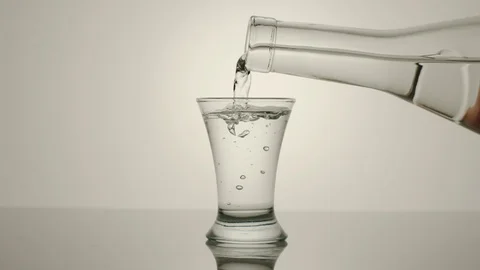 SLOW MOTION: Pouring vodka from a bottle into a glass - Side View Stock Footage 101816834