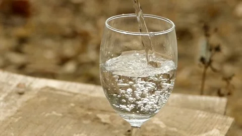 Slow-motion: Pouring water into a drinking glass on white background. splas.. Stock Footage 265844115