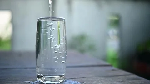 Slow motion of pouring water from a spring water into a glass on wooden table Stock Footage 265842151