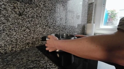 Slow motion POV close up of hands placing a stainless steel pot on a black Stock Footage 335393946