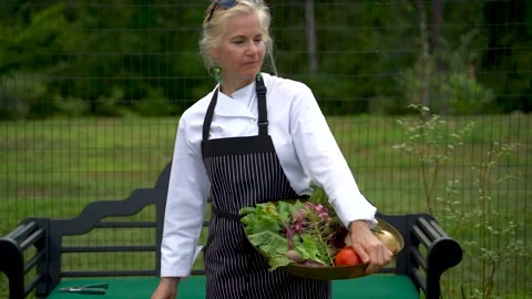 Slow motion pretty blonde chef farmer wipes her brow and walks through garden Video stock 135830419