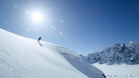 Slow motion of Pro athlete freeriding in powder snow with sun and blue sky Stock Footage 129119276