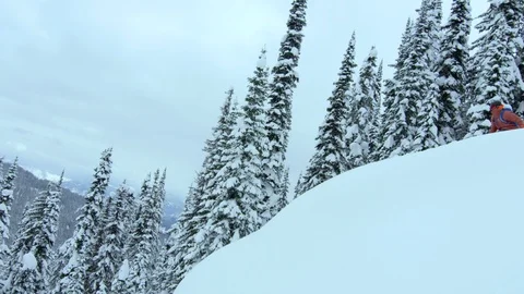 Slow motion of pro skier in red suit doing backflip on steep snowy hill, Canada Stock Footage 129095862