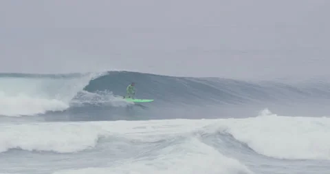 Slow motion of pro surfer Garrett McNamara surfing on small ocean wave Stock Footage 156005649