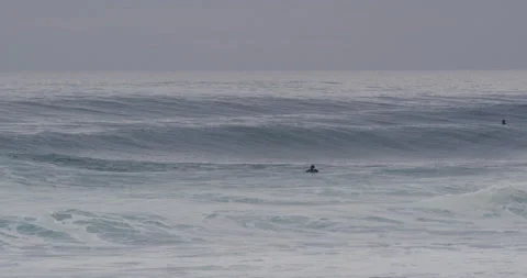 Slow motion of pro surfer paddling on surfboard to ocean wave during cloudy day Stock Footage 156004435