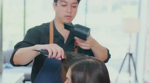 Slow motion. Professional Asian barber  beauticians are using blow dryers and Stock Footage 153882575