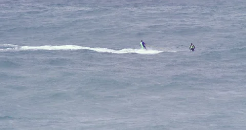 Slow motion of professional surfer being carried by fellow surfer on jet ski Stock Footage 156132658