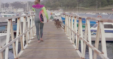 Slow motion of professional surfer Maya Gabiera walks across wooden pier Stock Footage 157134159