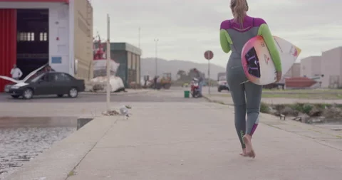 Slow motion of professional surfer Maya Gabiera walking across harbour barefoot Stock Footage 157134508