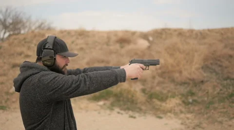 Slow Motion Profile of Man Shooting Two Handguns Stock Footage 60690818