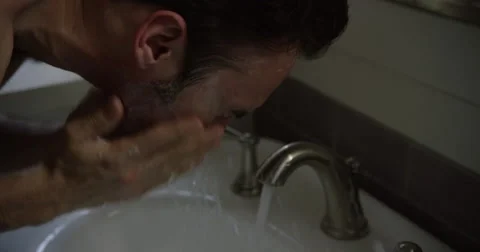 Slow motion profile of a White man rinsing his face with tap water. Video stock 64036024