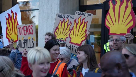 In Slow Motion Protestors Hold Up Placards Depicting The Shell Oil And Gas Stock Footage 310385606