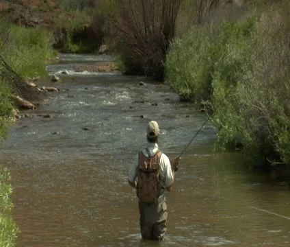 Slow motion pull out shot of fly fisherman and red rock cliffs Stock Footage 21679965