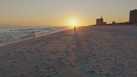 Slow motion push in drone shot of sunset on Pensacola beach at sunset woman Stock Footage 302192344