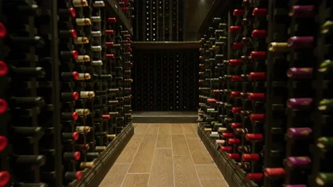 Slow motion pushing through rows of wine in dark home wine cellar Vidéo 204712897