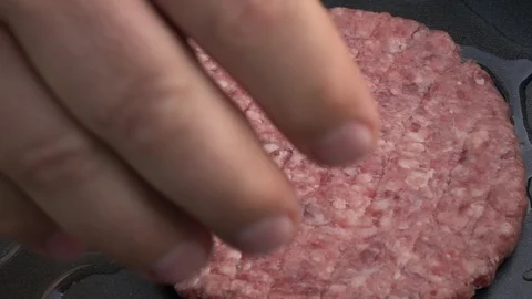 Slow motion of putting fresh hamburger on dark gray fry pan close up. Stock Footage 99853372
