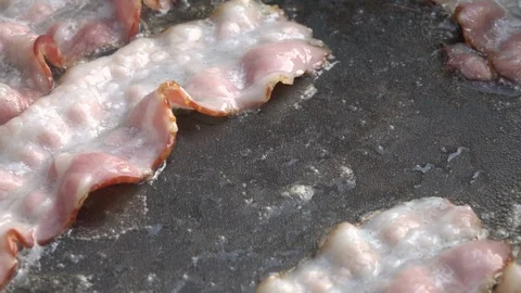Slow motion of putting sliced bacon on dark gray fry pan close up. Stock Footage 99851684