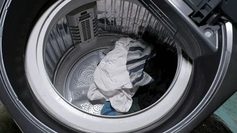Slow motion of putting their used clothes in the washing machine. Stock Footage 139186350