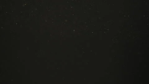 Slow motion rack focus of dust particles float in sunlight on black background Stock Footage 150681354