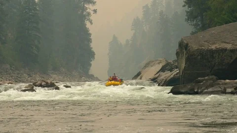 Slow motion raft floating down a river through forrest filled with smoke Stock Footage 80637070