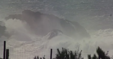 Slow motion of raging ocean waves splashing against big boulders on foggy day Stock Footage 156133597
