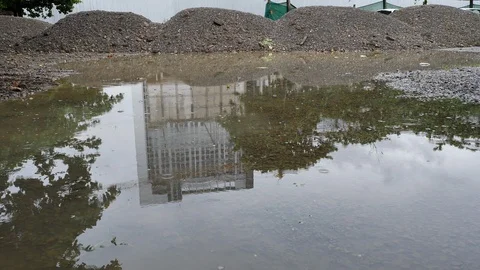 Slow motion rain drop on water puddle with reflection of building Stock Footage 94168098