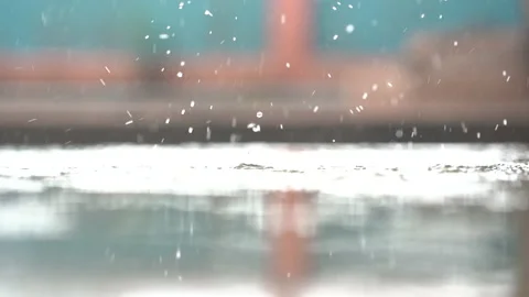 Slow motion rain droplets falling on ground on blurred background Video stock 140121857