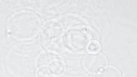 Slow motion rain drops and ripples on water surface on white abstract background Video stock 242062980
