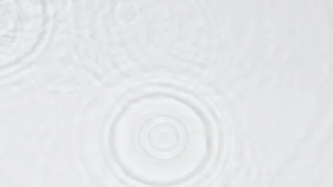 Slow motion rain drops and ripples on water surface on white abstract background 動画素材 246345979