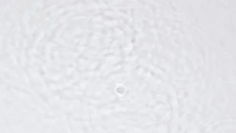 Slow motion rain drops on water surface over grey abstract background, top view. Stock Footage 204770919