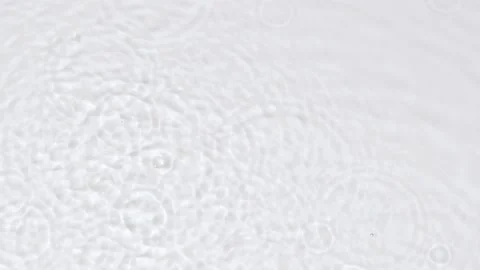 Slow motion rain drops on water surface over grey abstract background, top view. Stockbeeldmateriaal 213469800