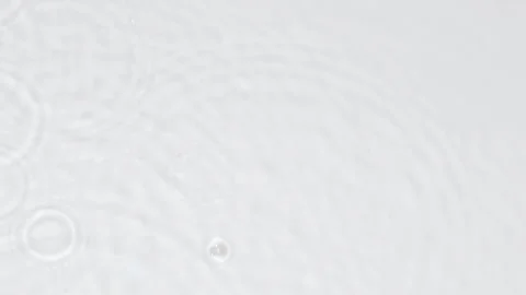 Slow motion rain drops on water surface over grey abstract background, top view. Stock Footage 218344015