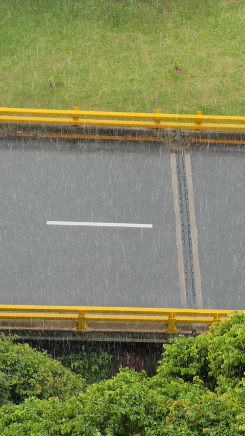 Slow motion rain falling on an empty asphalt road with yellow guardrails Stock Footage 311553233