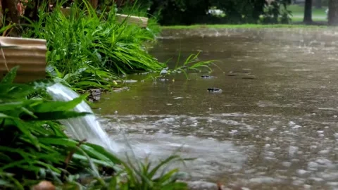Slow motion rain gushing from downspout onto a driveway during thunderstorm Vídeo Stock 154385829