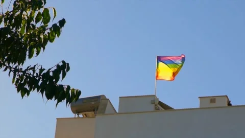 Slow motion of rainbow flag fluttering on rooftop in Sevilla, Spain Stock Footage 307571050