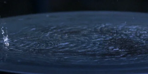 Slow-motion raindrops falling and splashing into the puddle Stock Footage 103748477