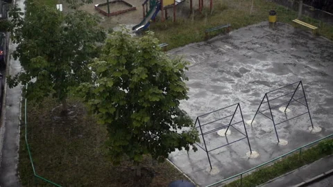 Slow motion raindrops falling on trees and a city playground Stock Footage 120516929