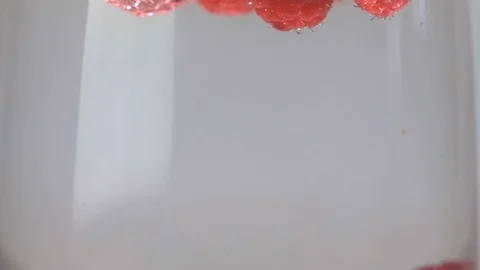 Slow motion raspberries floating and splashing into glass of water up close 動画素材 105277257