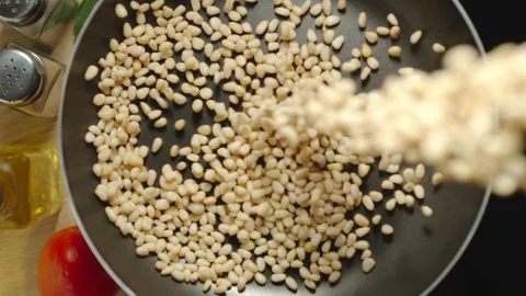 SLOW MOTION: Raw Peeled Cedar Nuts Being Poured On The Black Frying Pan Видео 118789053