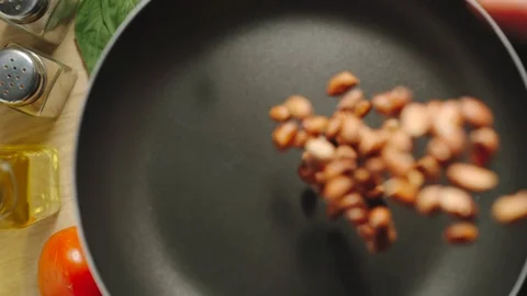 SLOW MOTION: Raw Peeled Peanuts Being Poured On The Black Frying Pan Vídeo Stock 118789019